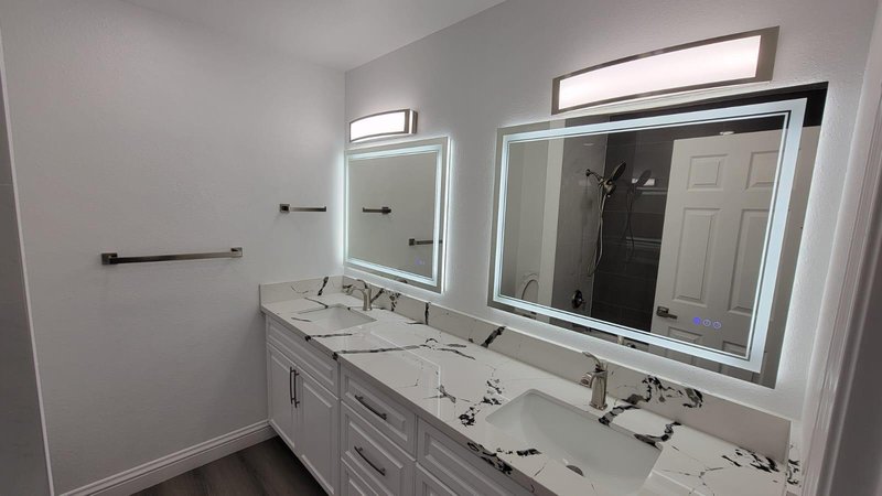 Baño con doble lavamanos, countertop de cuarzo y espejos LED