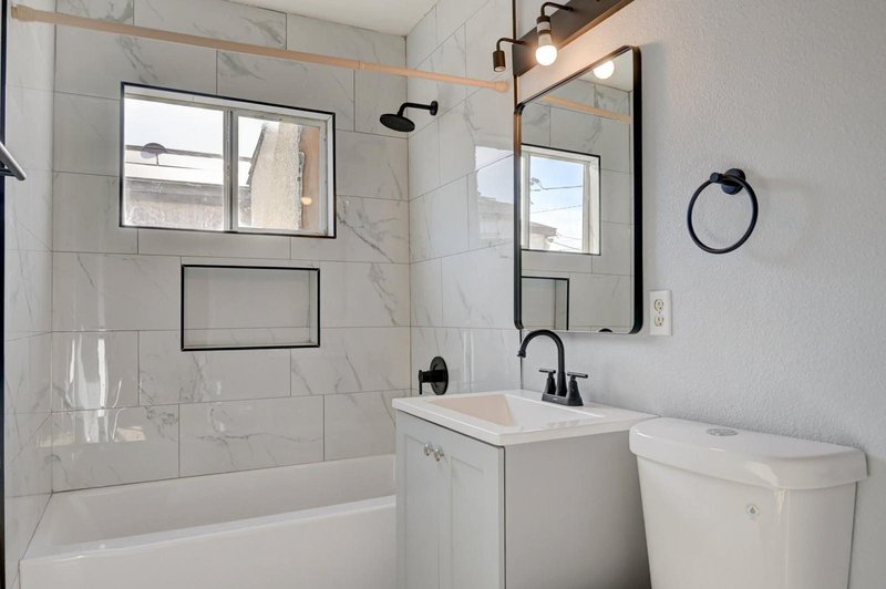 Baño con tile de mármol, tina y herrajes negros instalado en Las Vegas