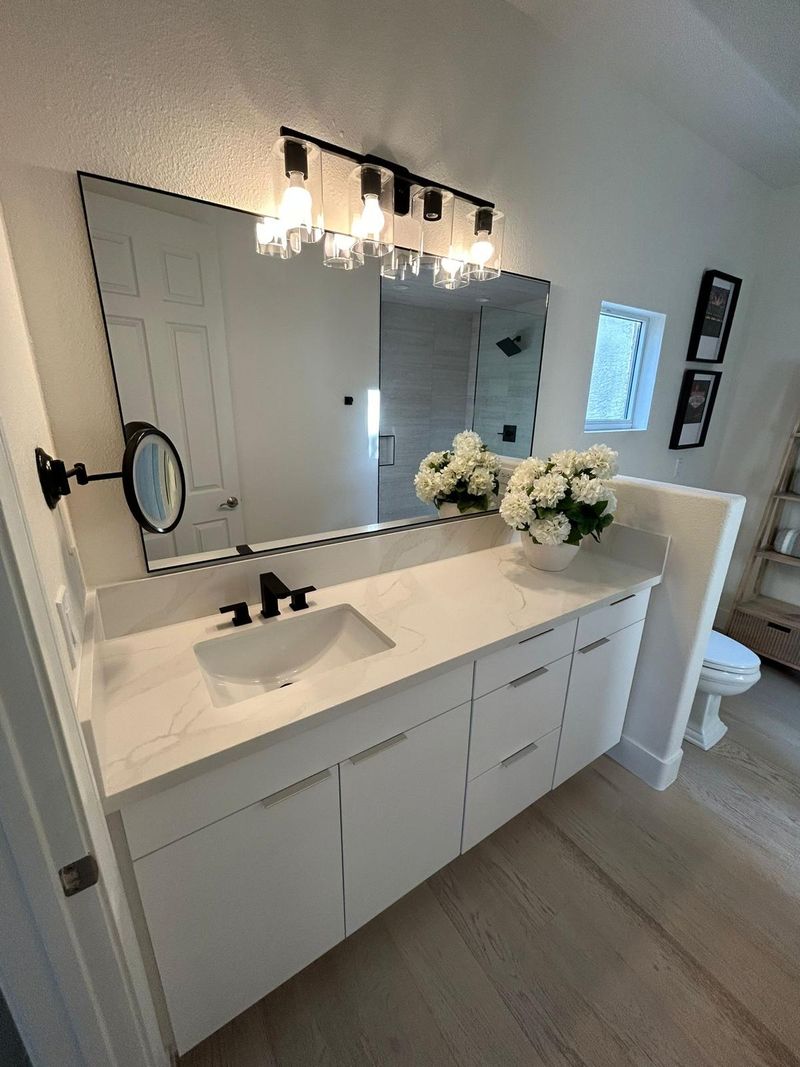 Baño remodelado con vanity blanca, countertop de cuarzo y grifería negra en Las Vegas