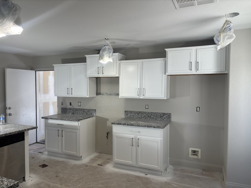 Instalación de gabinetes blancos y countertops de granito en proceso