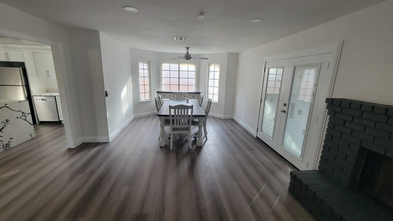 Comedor con piso LVP nuevo, paredes pintadas y chimenea de ladrillo pintada de negro