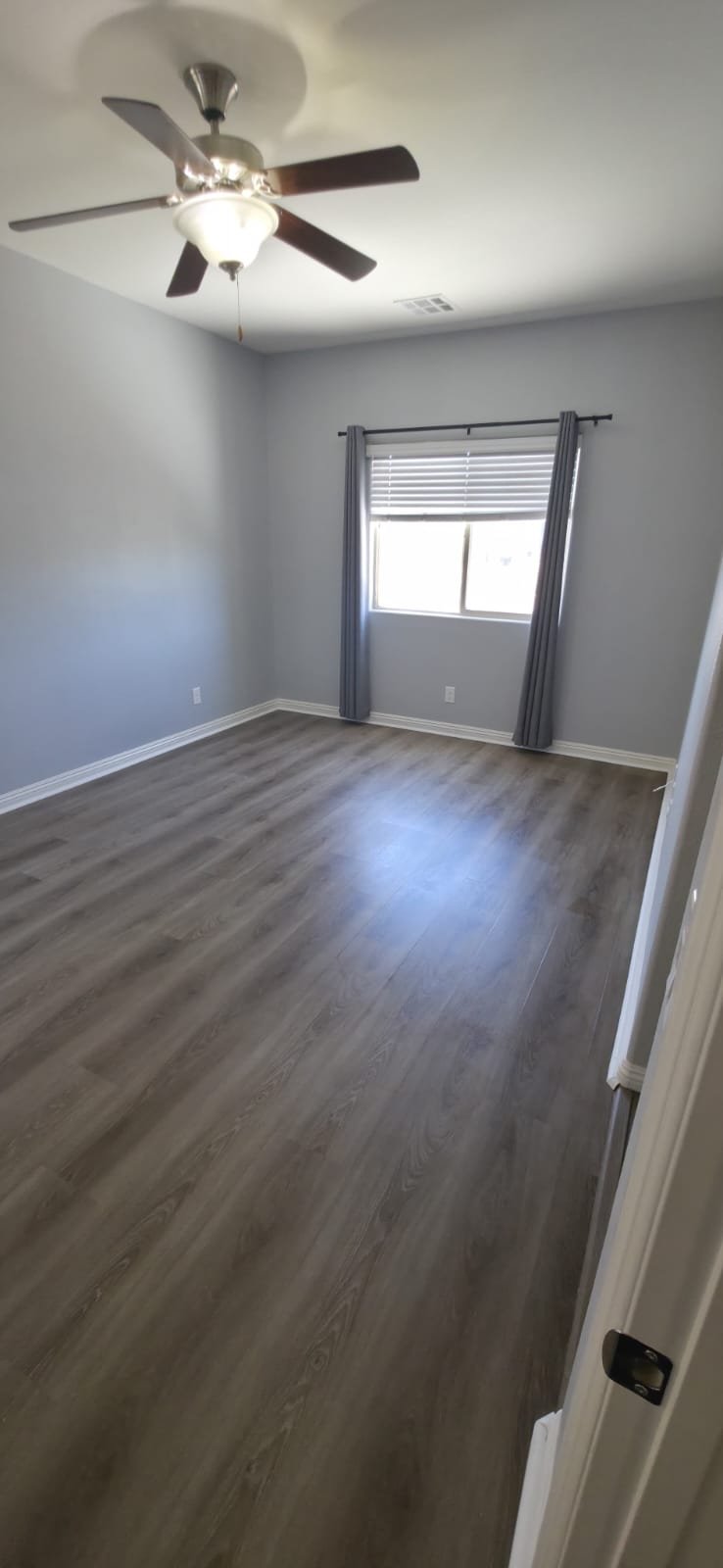 Habitación con piso LVP gris oscuro y baseboards blancos