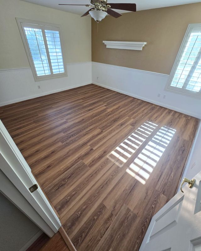 Bedroom with wood-tone SPC flooring and white wainscoting